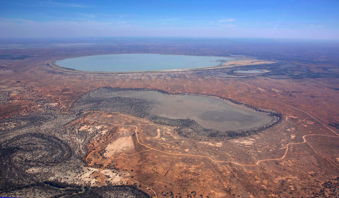 An aerial view of a large, dry lakebed in a desert landscape, depicting simple joys becoming mainstream.