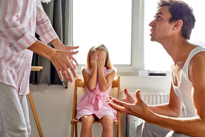 Parents arguing intensely while their young daughter covers her face, illustrating dumb ways people ruin their lives.