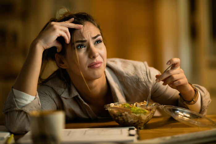 A woman expresses distress while eating, contemplating an unexpected end to a life story.