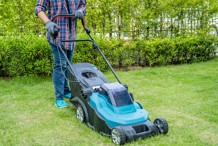 A person pushing a lawnmower on a green lawn, representing the everyday aspects of a life story.