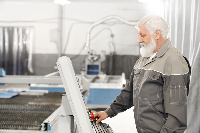 A senior man operating industrial machinery, representing potential problems society could be facing in the future.