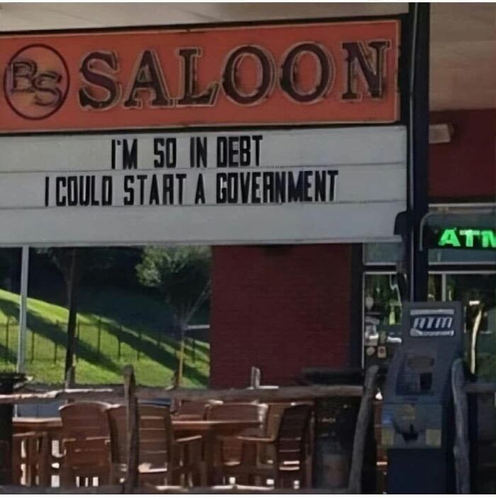 A Saloon sign with funny signs saying 'I'm so in debt I could start a government'.