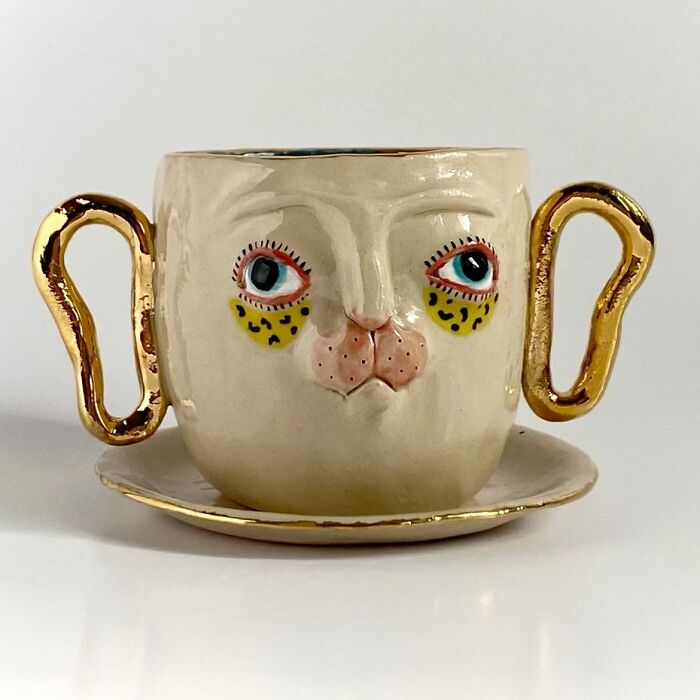 Weird ceramic sculptures mug featuring a stylized face with golden handles as home decor
