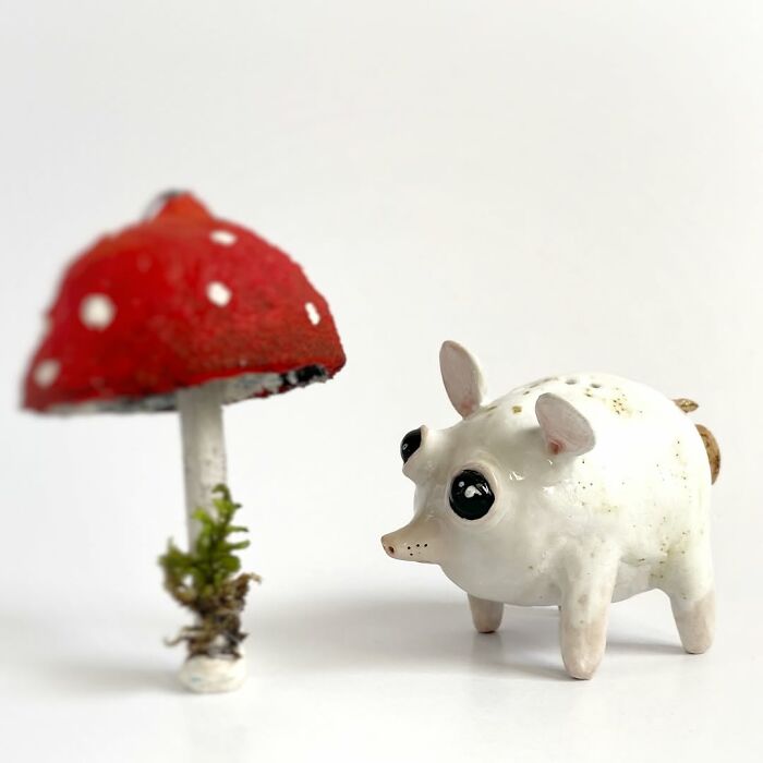 Small white pig-like weird ceramic sculptures next to a red mushroom as home decor