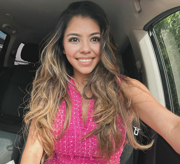 A smiling female lawyer taking a selfie in her car.
