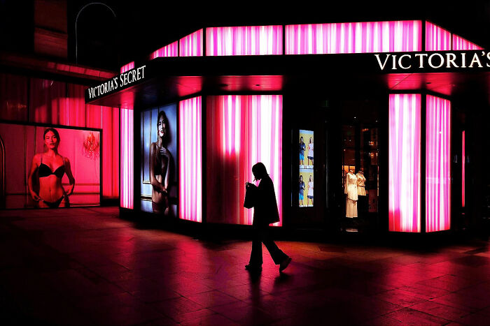 A photographer captures everyday architecture into a bold minimalist scene of a Victoria's Secret store at night, with a person walking past.