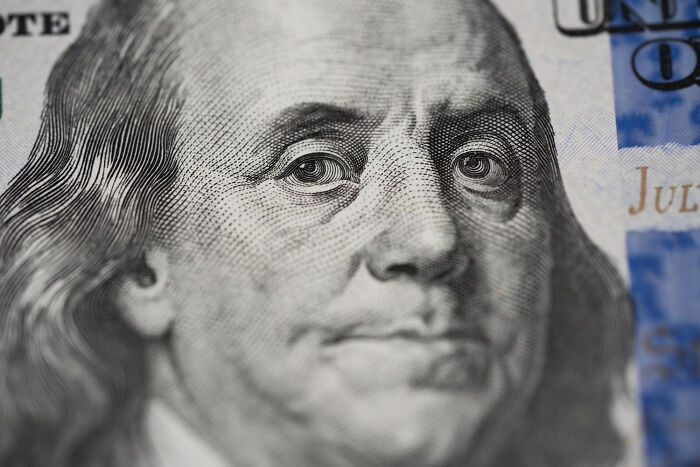 A close-up of Benjamin Franklin on a hundred-dollar bill, representing financial problems society could face.