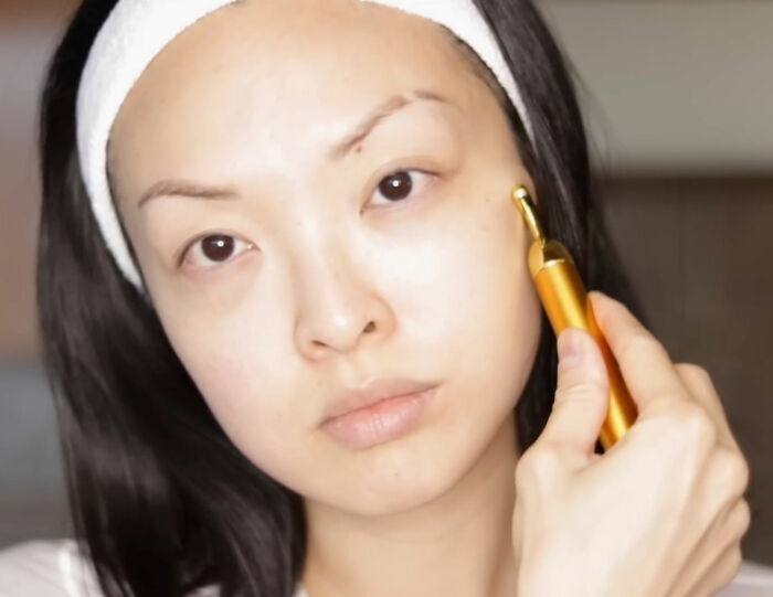 Japanese woman using a facial massager, challenging Western beauty standards with natural beauty. Japanese woman using a facial massager, challenging Western beauty standards with natural beauty.