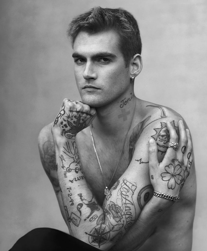 A black and white portrait of Presley Gerber showing his tattoos, hand resting on his chin. A black and white portrait of Presley Gerber showing his tattoos, hand resting on his chin.