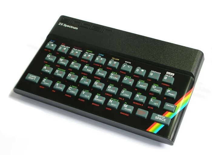 A Sinclair ZX Spectrum personal computer, an iconic piece of 80s retro tech, featuring a black case and a rainbow stripe.