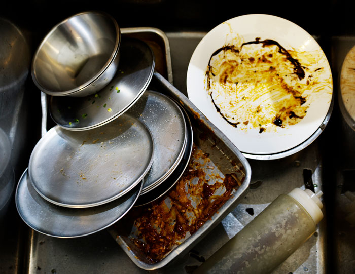Pile of dirty dishes in a sink, representing the neglected aspects of life when relationships become full-time headaches.