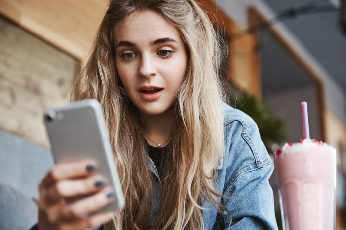 A woman doing crazy things to get a crush to like them, looking shocked at her phone.