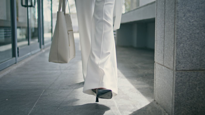 A person in white pants and heels walks away, carrying a bag, representing karma's instant repercussions.