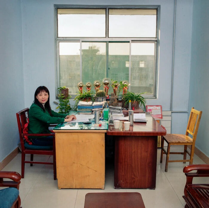 A woman sits at her desk in a government office, documenting the people and offices behind bureaucracy around the world.