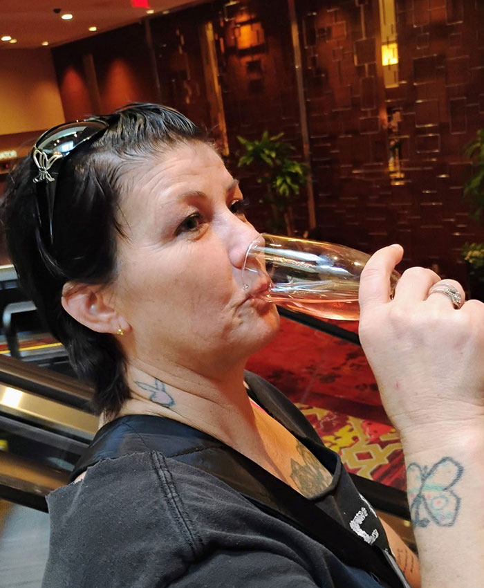 Woman with tattoos drinking from a champagne flute, related to the mom and son charged story.