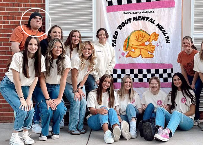 Sorority sisters pose together in front of a banner, with one member circled in the back.