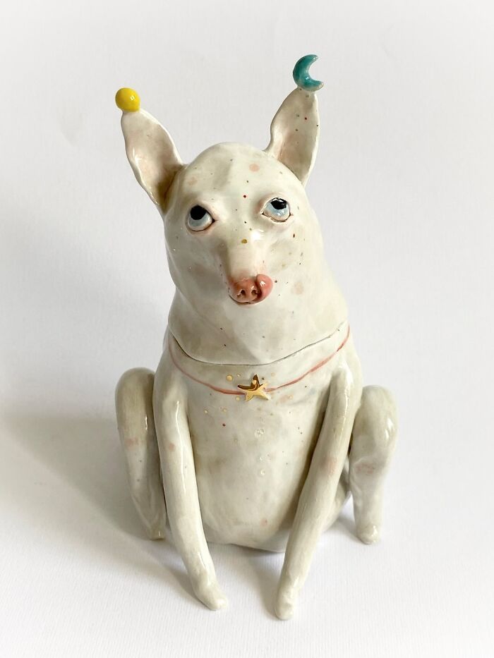 A quirky, hand-sculpted white dog ceramic sculpture with stars and moon details, acting as unique home decor.