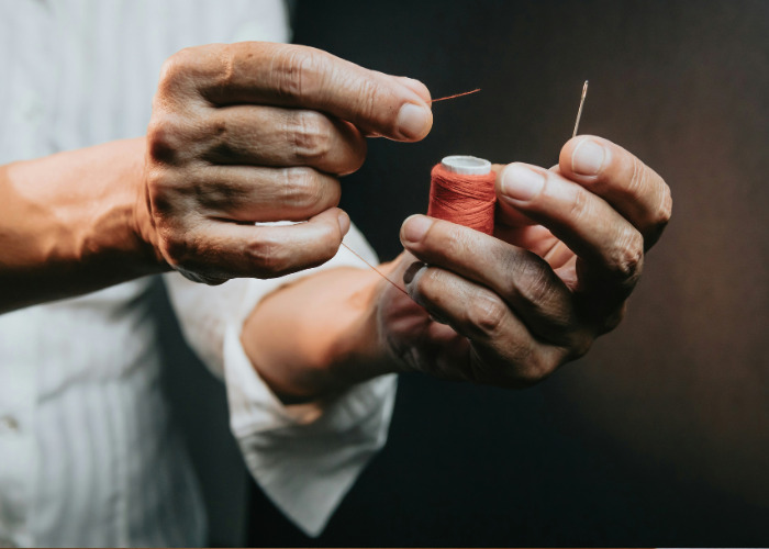 Man threading a needle preparing for sewing with thread