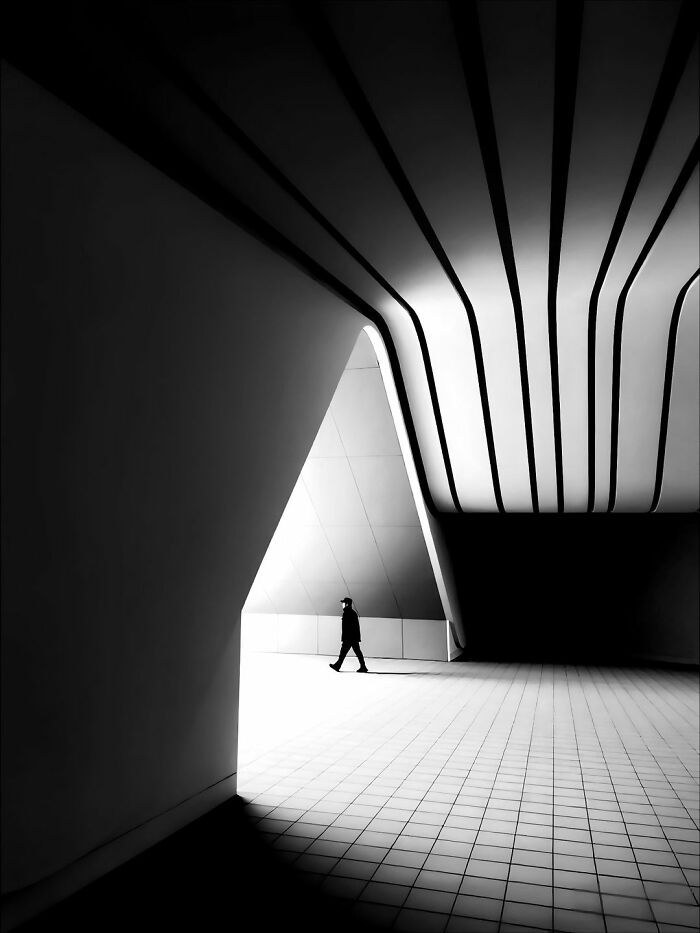 Minimalist architecture in black and white, featuring a person walking through a bright, geometric passage, creating bold scenes.