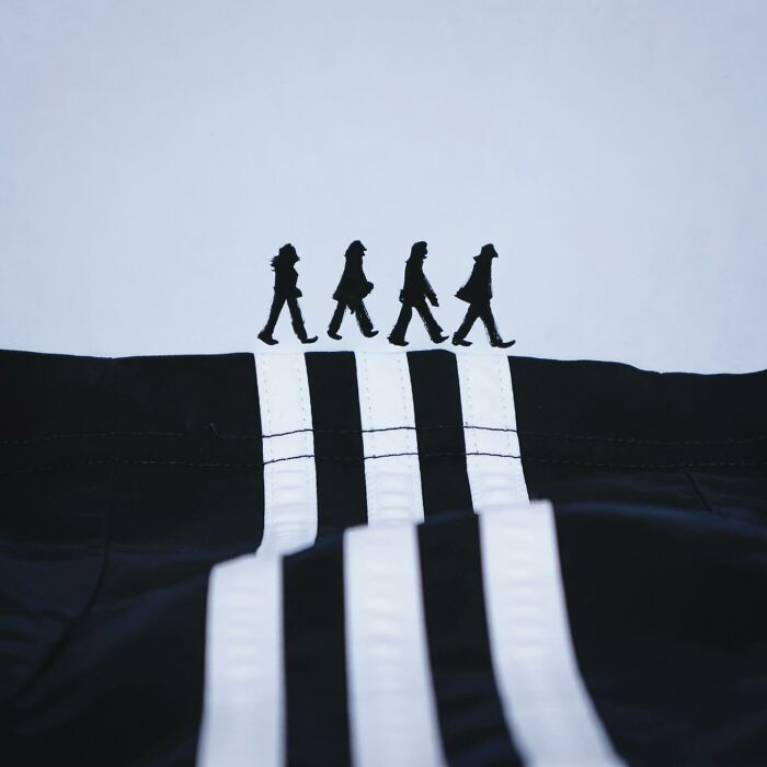 Playful illustrations featuring silhouettes walking on the white stripes of a black fabric track jacket