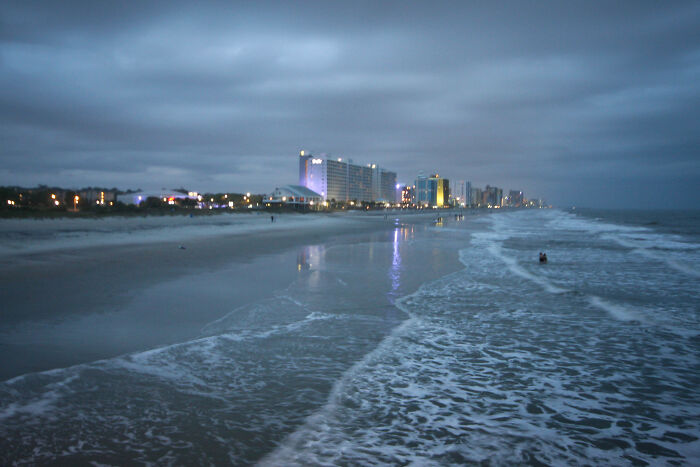 A beach at dusk with a city skyline, reflecting on simple joys that are now mainstream.
