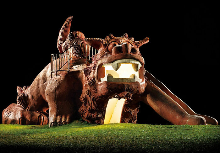 A large brown lion-like creature playground slide at night, a surreal Japanese playground by Fujio Kito.