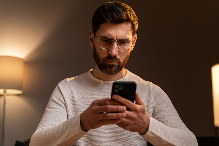 A man looking intently at his phone, thinking about marriage and what he wish he knew before divorce.