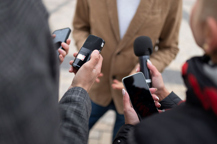Reporters interviewing a person outdoors, capturing the story of students' loud parties and home bar. Reporters interviewing a person outdoors, capturing the story of students' loud parties and home bar.