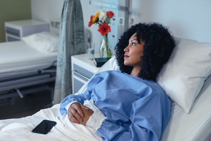Woman in a hospital bed suffering from a post C-section infection, feeling unwell.
