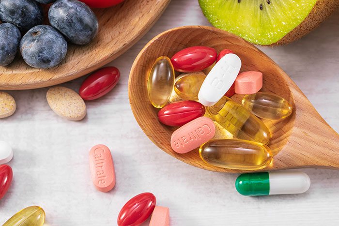 Various vitamins and supplements in spoons and on a table. The ashwagandha gummies are a viral product that can cause liver failure.
