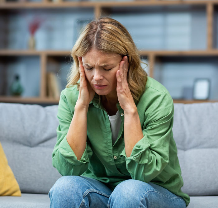 A woman suffering from a headache, illustrating the health issues like liver failure caused by viral Ashwagandha gummies.
