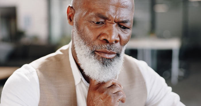 Close-up of a thoughtful, grey-bearded grandad, contemplating the woman's post C-section infection claims.