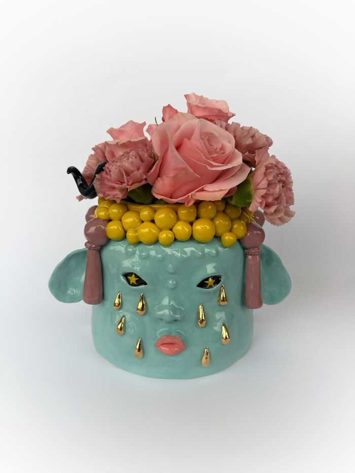 Teal weird ceramic sculptures vase with a crying face holding pink roses as home decor