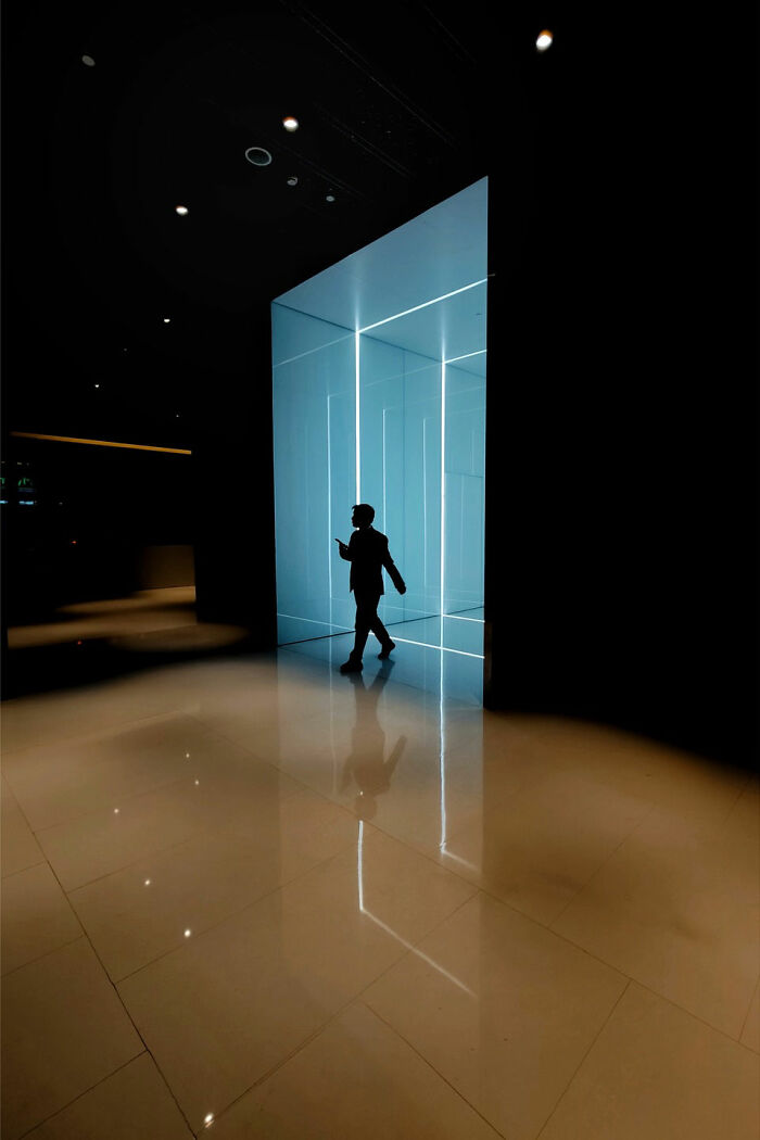 A photographer captures minimalist architecture with a person silhouetted against a luminous doorway, showcasing bold scenes.