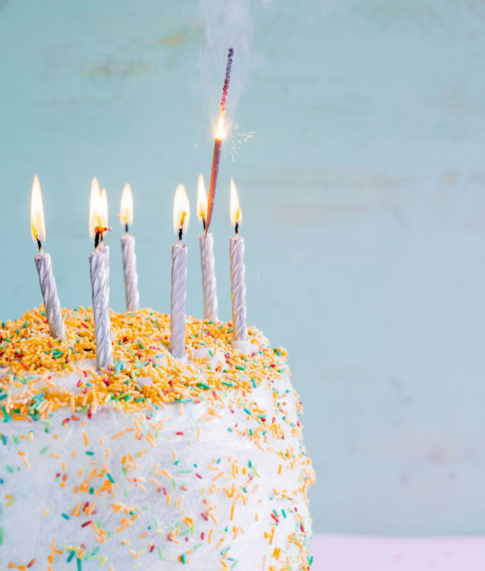 Birthday cake with lit candles and a sparkler, representing the beginning of a relationship that can lead to headaches.