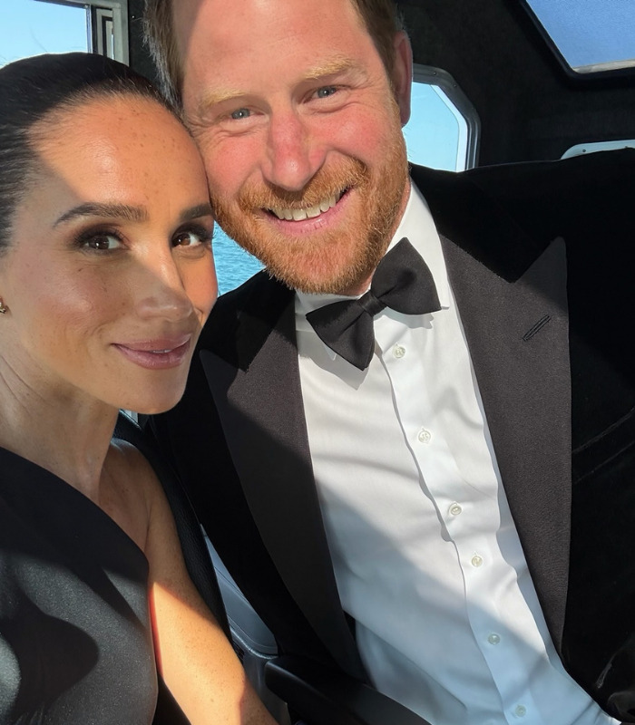 Prince Harry and Meghan looking at the camera, smiling together, potentially discussing the King Charles letter. Prince Harry and Meghan looking at the camera, smiling together, potentially discussing the King Charles letter.