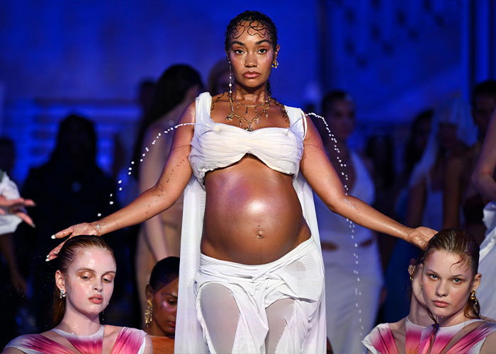 Leigh-Anne Pinnock as a pregnant star on a runway featuring gushing liquid sprays