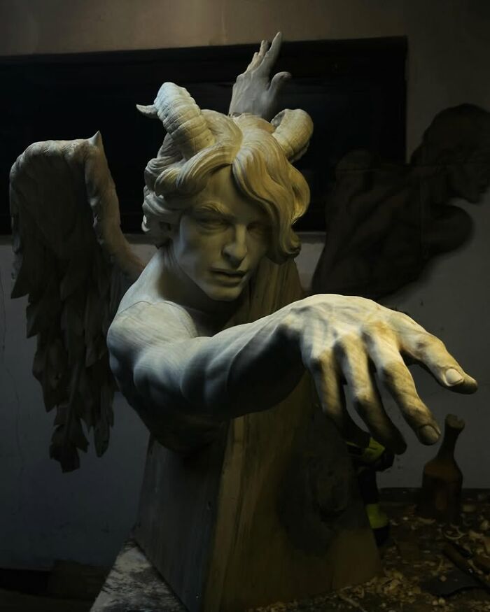 A lifelike wood sculpture of a winged demon with horns, showcasing detail from a Polish artist