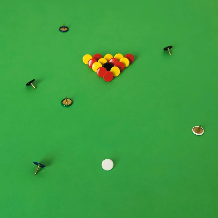 Playful illustrations of colorful pushpins arranged like a game of pool on a green surface