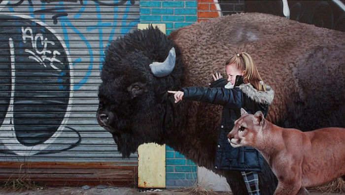 A child with a large bison and mountain lion in dystopian paintings by Kevin Peterson against a graffiti garage door