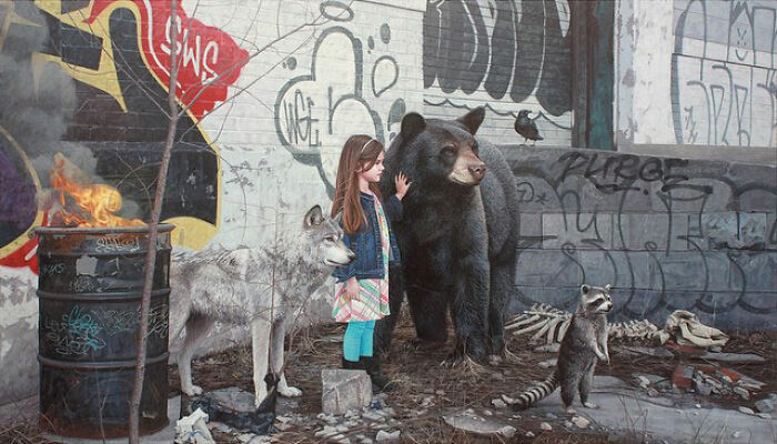 A girl stands with a wolf, a bear, and a raccoon by a fire barrel in dystopian paintings by Kevin Peterson.
