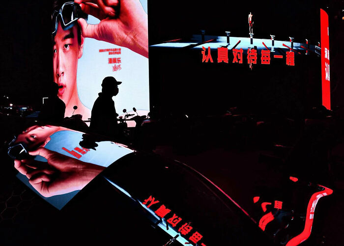 A photographer captures everyday architecture into a bold minimalist scene of a large LED screen displaying a man with sunglasses and red text.