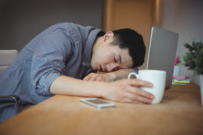 Exhausted man sleeping at his desk, capturing the fatigue experienced by some strange patients.