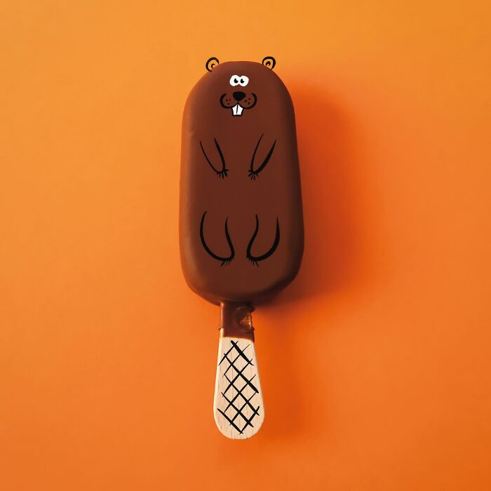 A playful illustration of a chocolate ice cream bar on a stick reimagined as a beaver on an orange background
