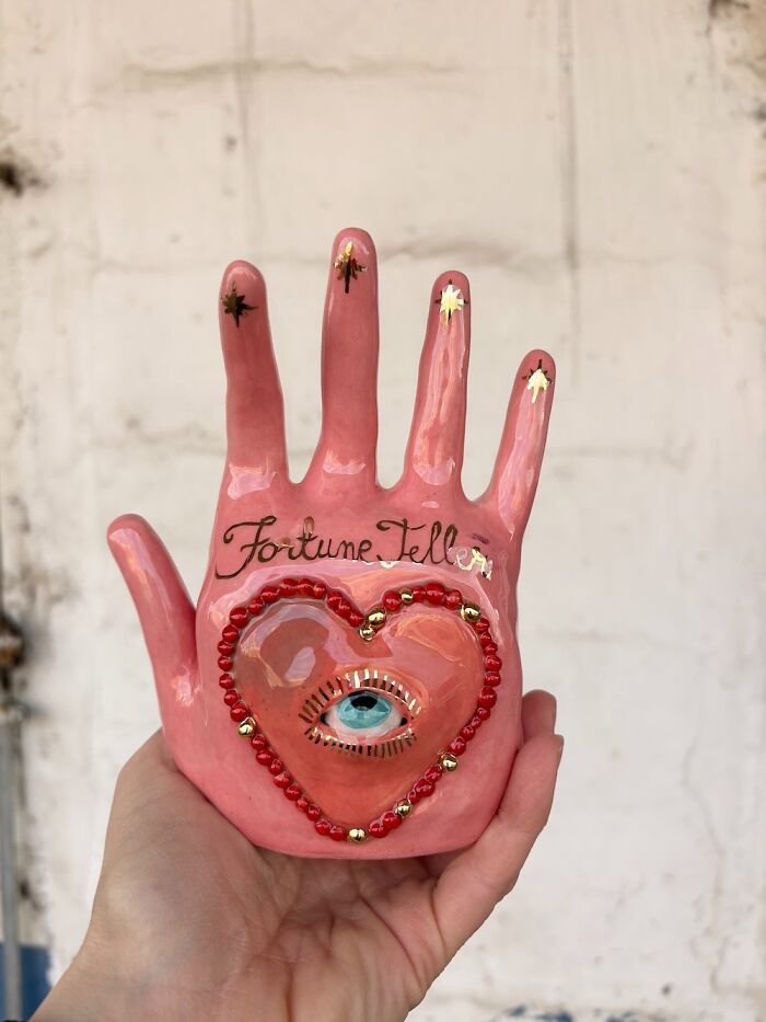 Pink fortune teller hand ceramic sculpture featuring a heart with an eye, serving as unique home decor.