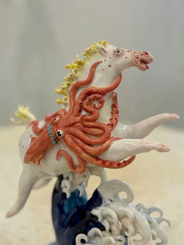 Weird ceramic sculptures of a white horse with yellow mane being hugged by a pink octopus on a blue wave.