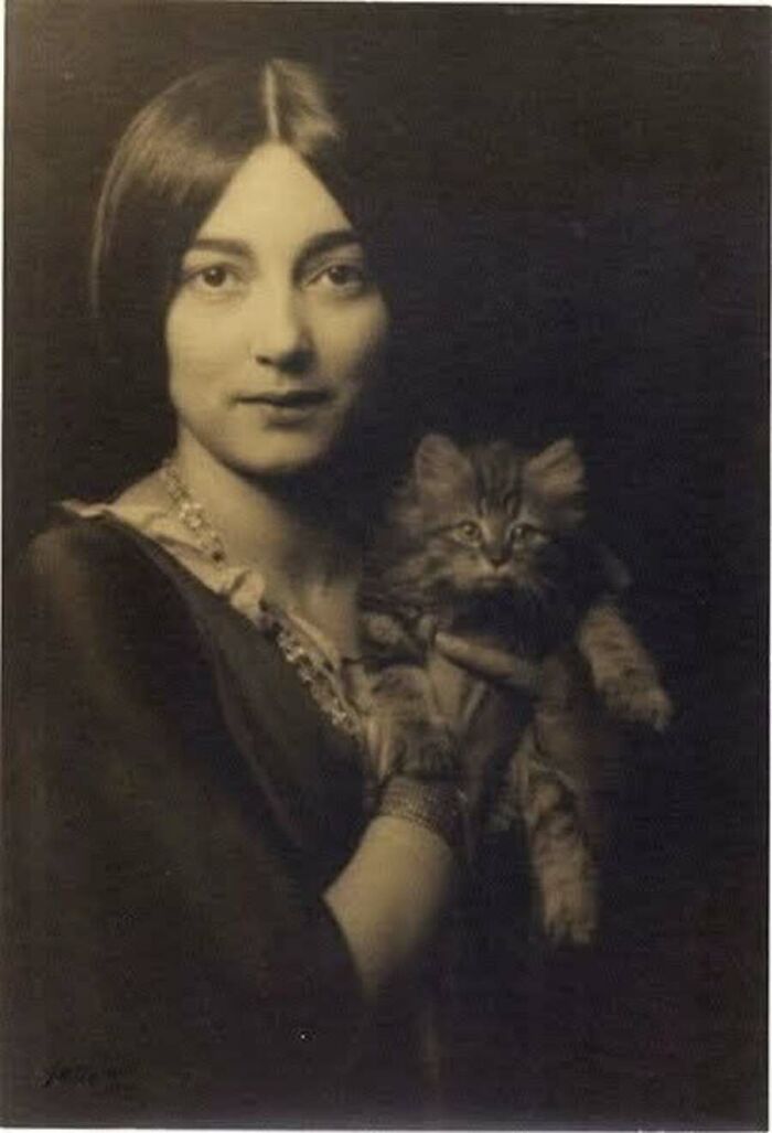 Vintage cat photo of a young woman with a classic middle part holding a fluffy kitten