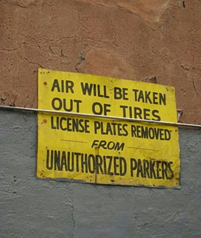A funny sign warning unauthorized parkers that air will be taken out of tires and license plates removed.