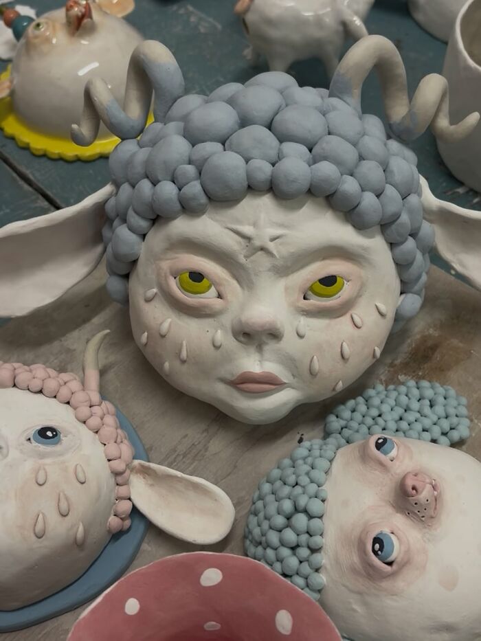 An in-progress weird ceramic sculpture of a horned creature face with blue hair.
