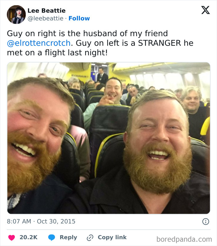 Two bearded men, one a stranger, appear to be synchronized, smiling broadly on an airplane. Amazing times synced.